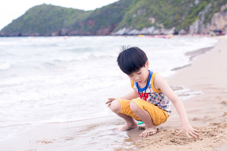 在海滩上的小亚洲男孩玩沙