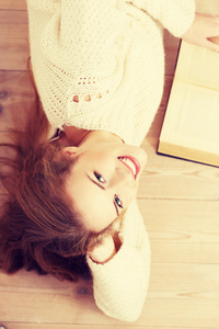 美丽的女人躺在地板上的书