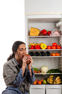 饿女人吃肉坐在冰箱里