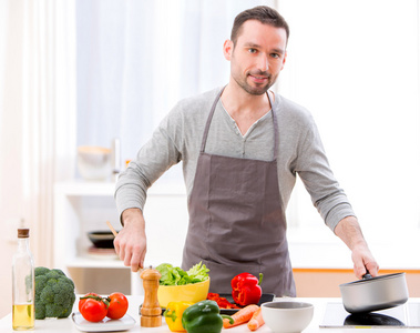 年轻有魅力的男人在厨房做饭