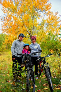 秋天的公园，父母和孩子骑自行车自行车上的家庭