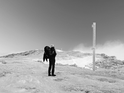 大背包和雪鞋站在前面的路标和旅游。国家公园在意大利阿尔卑斯山公园。阳光和楣冬天的早晨