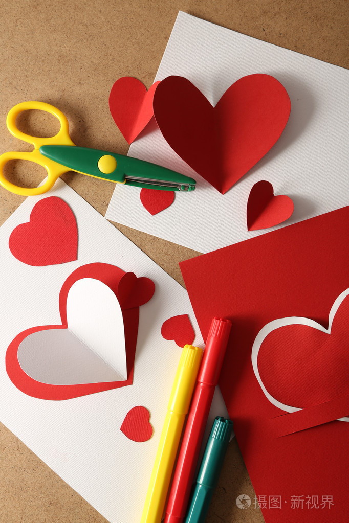 美丽的手工制作的明信片, 笔和剪刀用纸心颜色木制背景