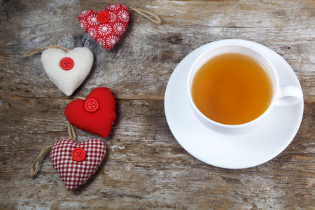 织物的心和杯茶木制背景