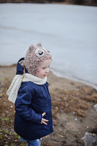 可爱的孩子女孩在蓝色的外套和猫头鹰帽子上在冰冻的湖面上行走