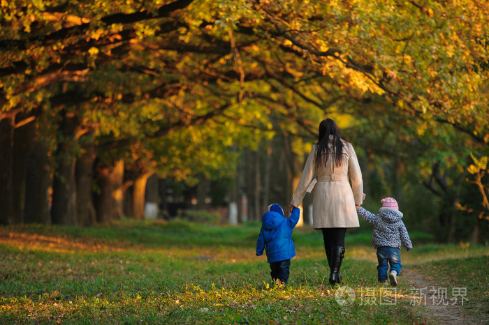 母亲带着孩子双胞胎在秋天公园散步