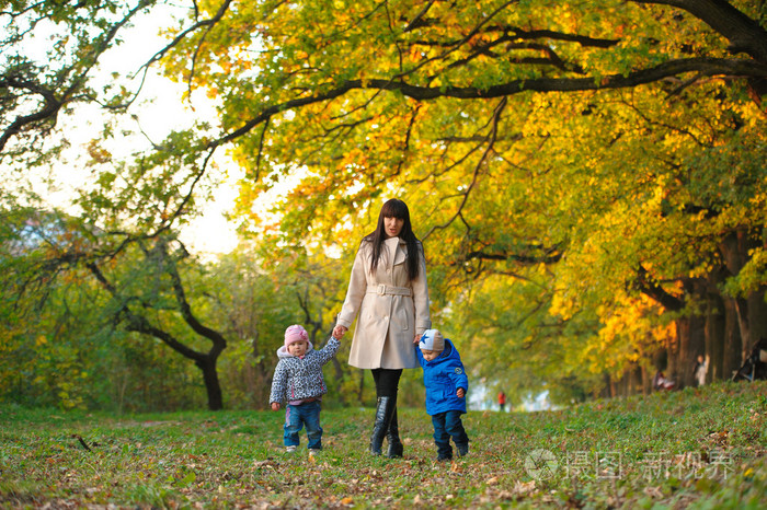 母亲带着孩子双胞胎在秋天公园散步