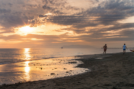 日落时两个人在沙滩上奔跑