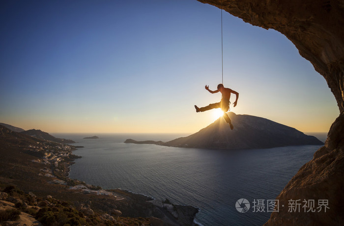 攀岩时铅日落时分，在背景中的 Telendos 岛攀爬绳子上挂着