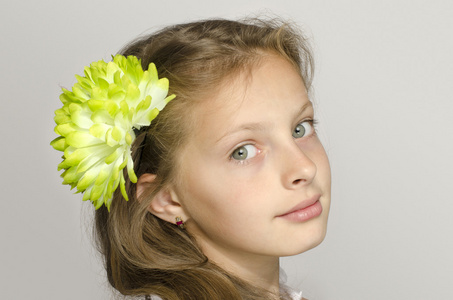 小女孩在她的头发,绿色的大花闻一朵花照片