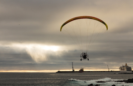 以上海上滑翔伞以上海洋港口的机动的滑翔伞飞行.照片
