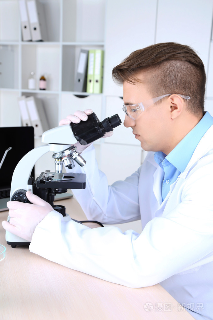 男性的科学家在实验室中使用显微镜