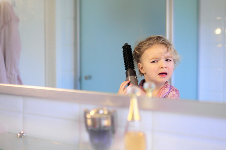 快乐的小女孩刷牙和造型她的头发