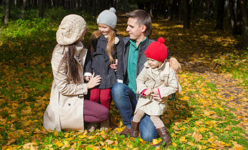 年轻的家庭和可爱的小女孩在秋天公园