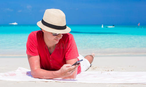 热带白色海滩上拿着手机的年轻人