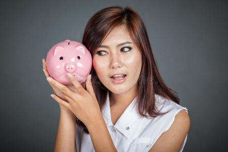 美丽的亚洲女孩想知道猪钱箱里有多少钱