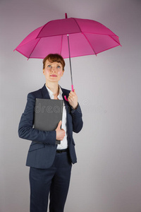西装革履的女商人拿着粉红色的伞和记事本