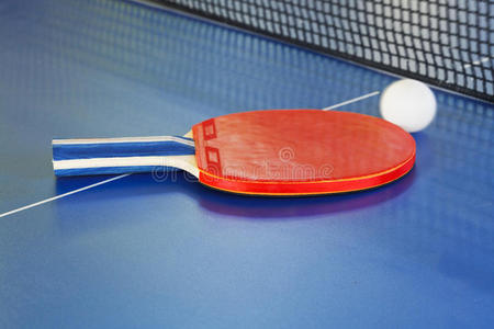 红色的球拍，蓝色乒乓球桌上的网球