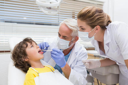 儿科牙医和他的助手给一个小男孩检查牙齿