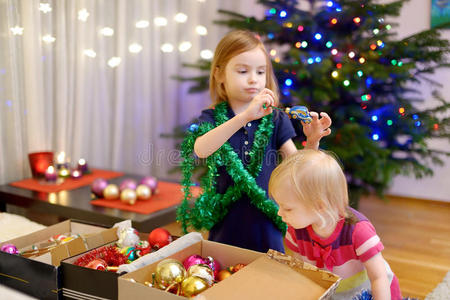 两个小姐妹在装饰圣诞树