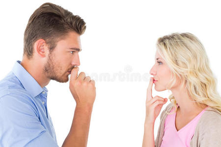一对年轻夫妇保持沉默，手指放在嘴唇上