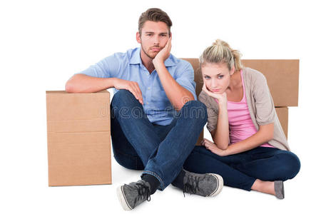 坐在搬家的箱子旁边的不幸的年轻夫妇