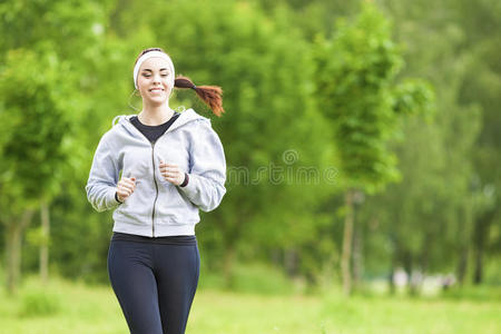 慢跑运动理念年轻的跑步健身女性在森林中一边听音乐一边开心地微笑