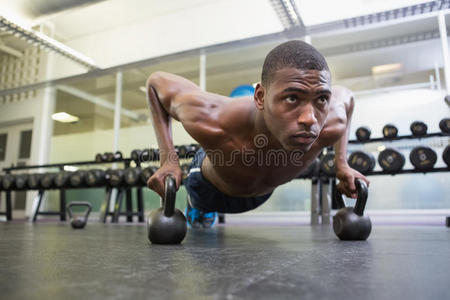 有决心的男人在健身房用水壶铃做俯卧撑