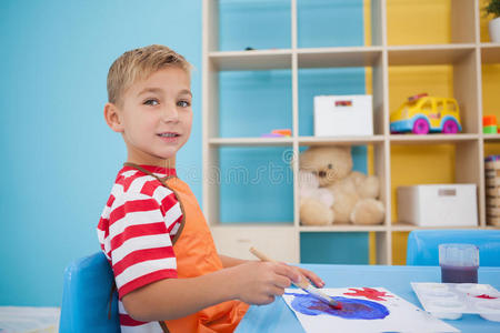 教室里可爱的小男孩在桌边画画