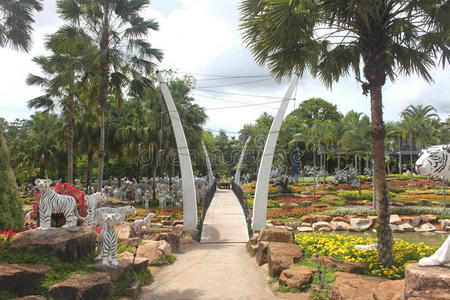 芭堤雅市附近的农家乐热带植物园中，一座有草地草地树木和石头的桥梁的远景
