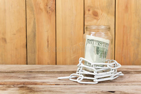 玻璃罐里的钱和木桌上的链条