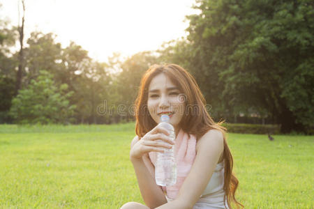 女人喝水，坐在草地上。