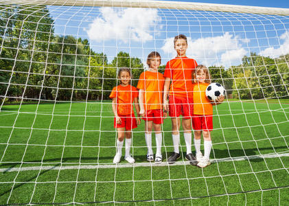 不同身高的孩子站在足球旁边