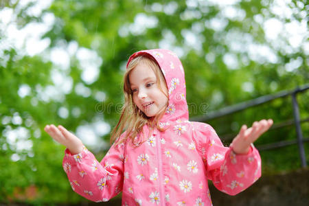 可爱的女孩快乐地站在雨中