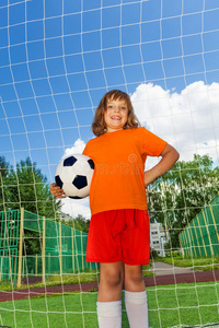 快乐女孩举着足球站在白网旁