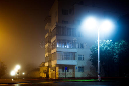 空旷的夜市街道上的公寓楼被大雾笼罩