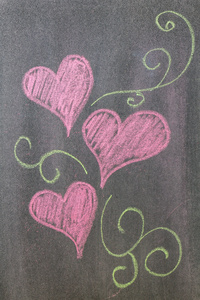 手在黑板背景上绘制的心的形状