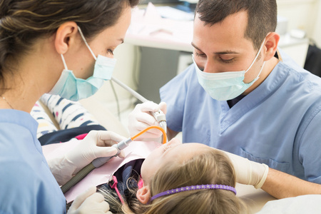牙医和牙科助理检查年轻女孩牙齿
