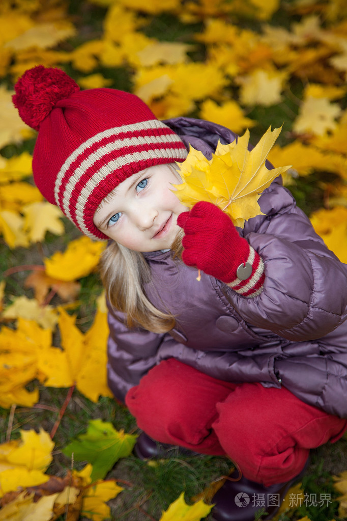 小女孩坐在中间秋天的落叶