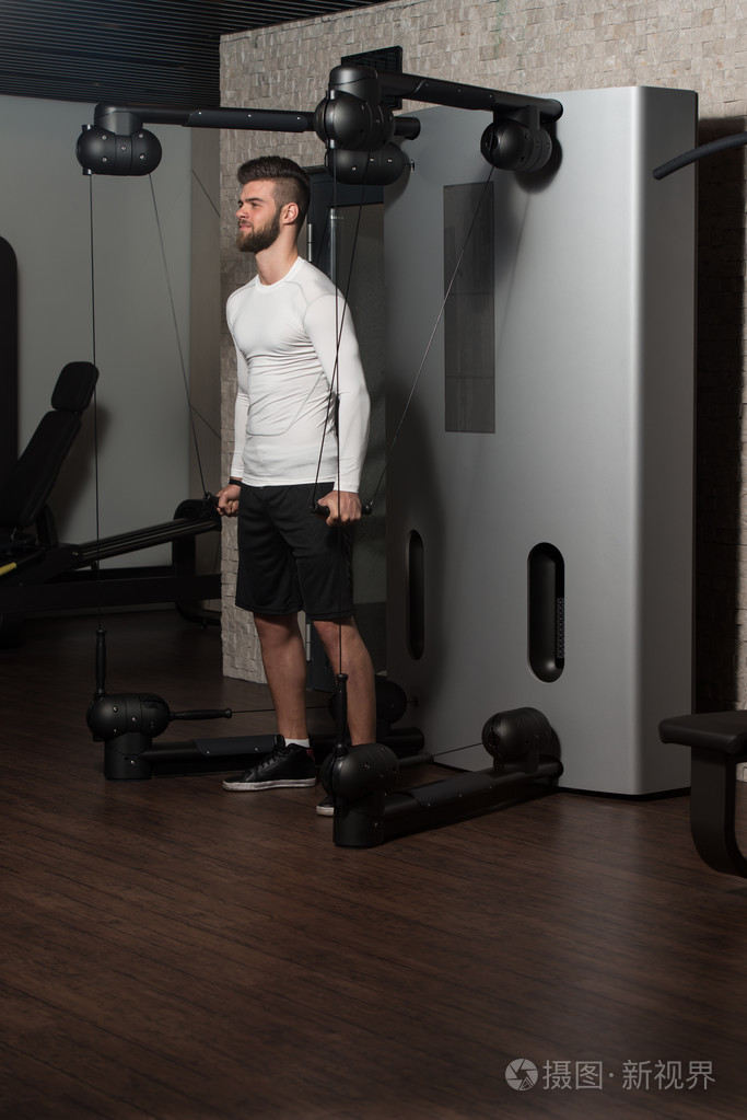 年轻男性在健身房里锻炼肩膀