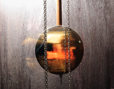 摆动的钟摆金属钟摆摆动在木背景照片