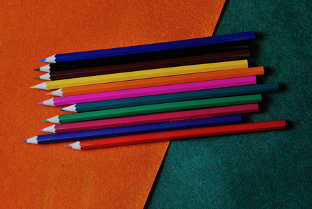 橙色和绿色抽象带纹理的背景上的五彩的铅笔