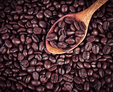 在木勺烘焙过的咖啡豆放咖啡豆作为背景