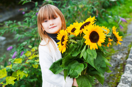 可爱的小女孩与花束的向日葵,在户外的肖像照片