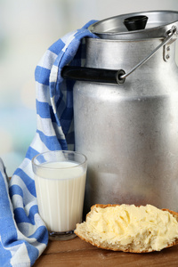 复古可以为牛奶新鲜面包和玻璃上木桌前，在明亮的背景上的牛奶。生物产品概念