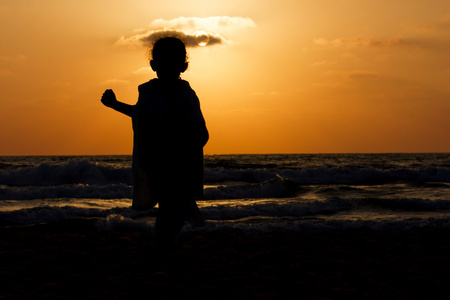 日落时海滩上小女孩的剪影