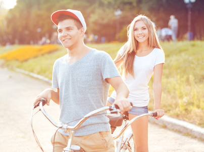 年轻的男人和女人在公园户外骑自行车