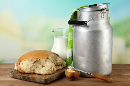 复古可以用新鲜的面包和牛奶在木桌子上，在明亮的背景上壶牛奶。生物产品概念