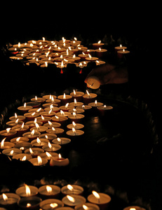 祷告的老年妇女和点燃一根蜡烛