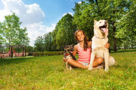 可爱的少女和她的狗在公园草坪上